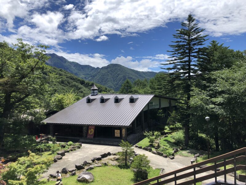 夏の青空と以前ビジターセンター内にあった日帰り温泉「神宝乃湯」の建物